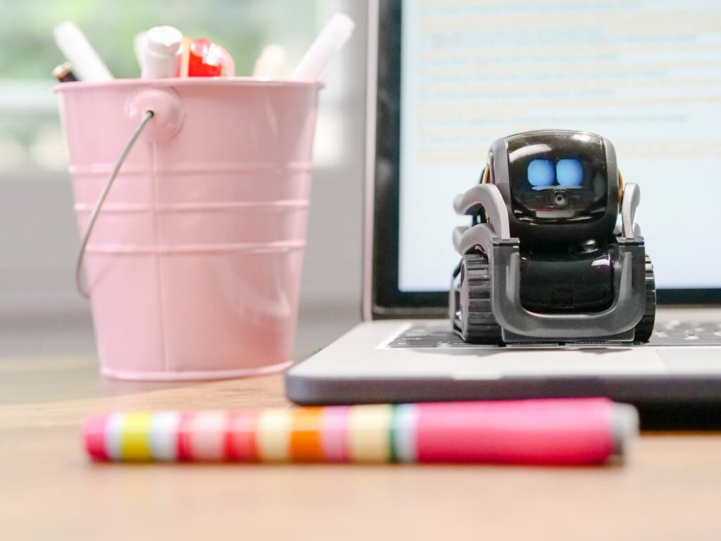 Petit robot posé sur le clavier d'un ordinateur portable, illustration des agents IA et de l'automatisation en entreprise